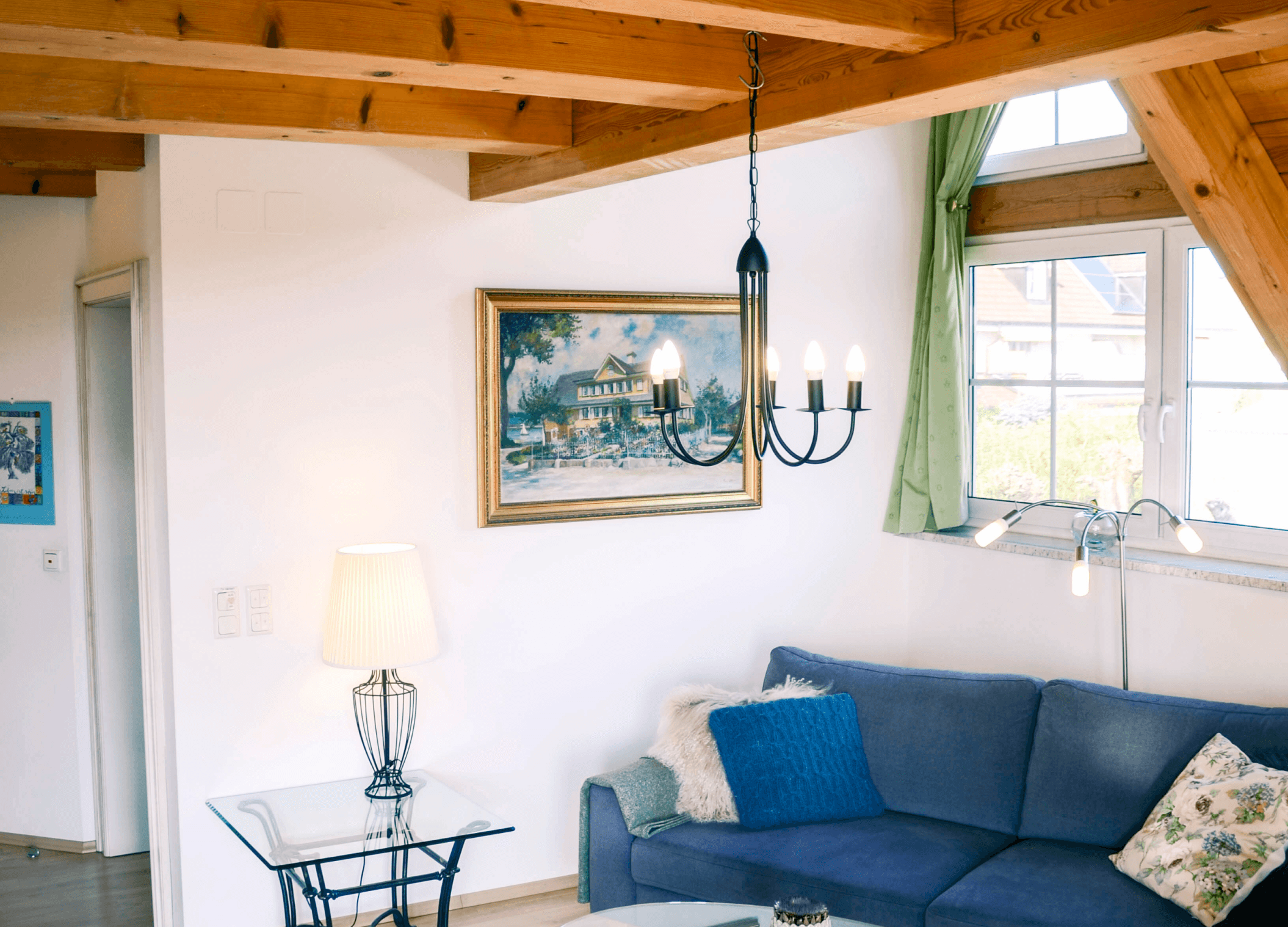 Wohnbereich der Ferienwohnung Silberfee mit Sofa unter offenem Holzdachstuhl